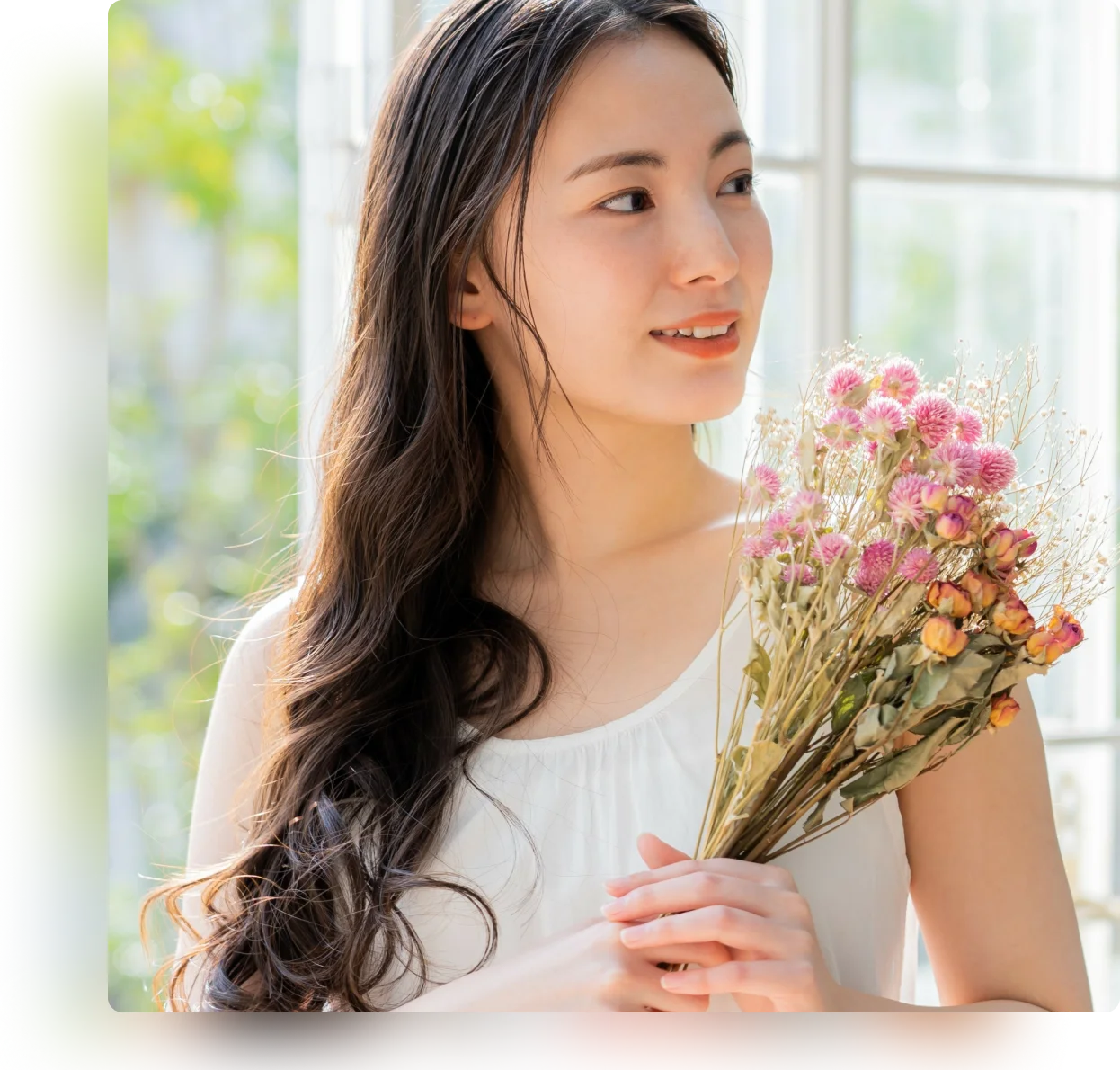 明るい窓辺で花束を持つ女性