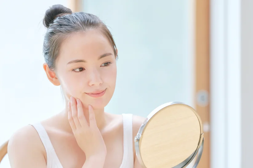 鏡を見ながら頬に手を添える女性